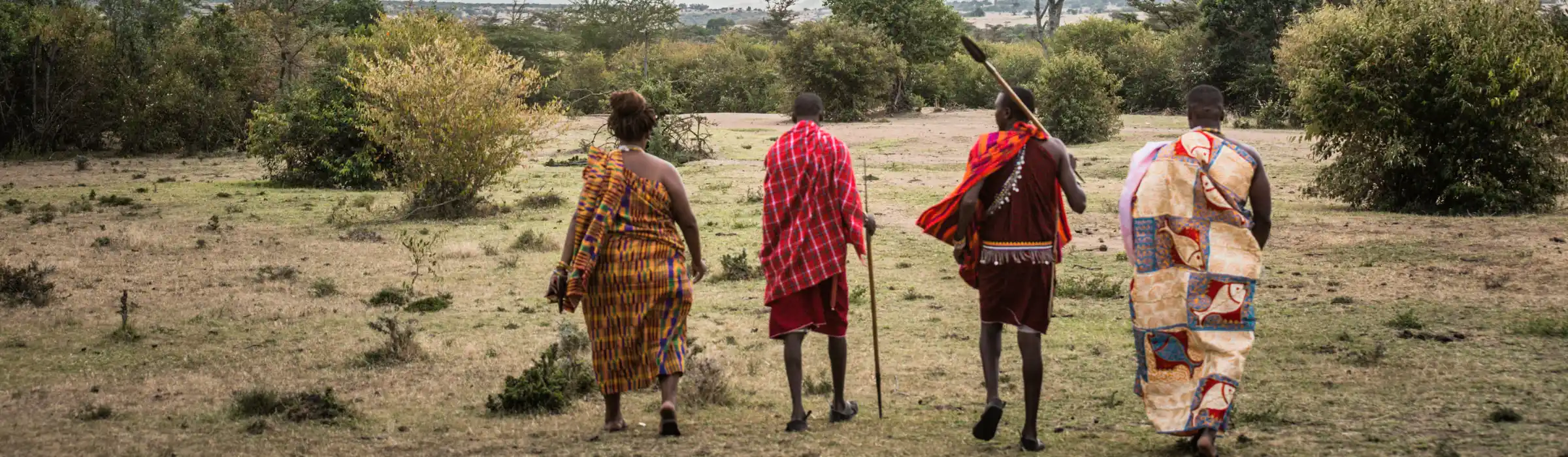 Maasai family in traditional dress walking through the savanna - cultural tourism experiences - Porcupine Tours